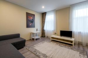 a living room with a couch and a flat screen tv at Kolumbs Junior Suite in Liepāja