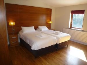a bedroom with a large bed with a wooden headboard at Castlemartyr Holiday Lodges 2 Bed in Castlemartyr