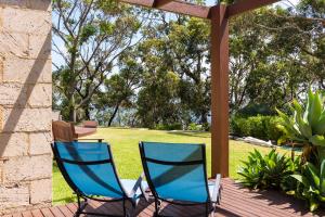 2 sillas azules sentadas en una terraza con jardín en By the Beach B&B Self Contained Apartments, en Sanctuary Point