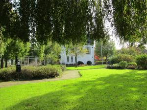 a green yard with a white house in the background at Herberg Welgelegen in Katwijk