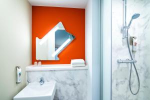 a bathroom with a sink, mirror, and bathtub at ibis budget Rotterdam The Hague Airport in Rotterdam