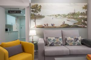 a living room with a couch and a painting on the wall at Atelier Plaza Nueva Plus in Seville