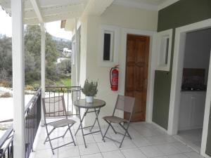 a porch with chairs and a table and a fire extinguisher at Sea Pebble Studios in Mikros Gialos