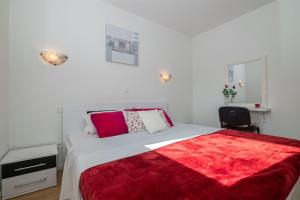 a bedroom with a bed with a red blanket on it at Apartment Matmar in Split