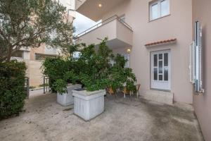 a house with a bunch of potted trees in a courtyard at Apartments Karolina in Novalja