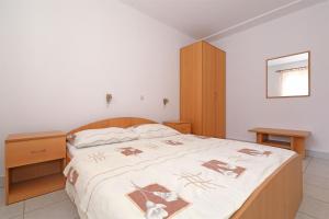 a bedroom with a large bed and a wooden cabinet at Apartments Karolina in Novalja