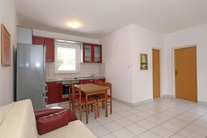 a kitchen and dining room with a table and a refrigerator at Apartments Karolina in Novalja