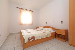 a small bedroom with a bed and a window at Apartments Karolina in Novalja