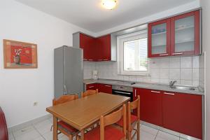 a kitchen with red cabinets and a wooden table at Apartments Karolina in Novalja