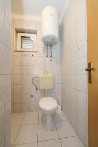 a bathroom with a toilet and a light on the wall at Apartments Karolina in Novalja