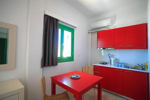 a kitchen with red cabinets and a red table at Kastellos Apartments Sikinos in Alopronia