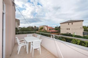 a balcony with a white table and chairs on it at Apartments Karolina in Novalja