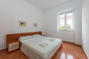 a white bedroom with a bed and a window at Apartments Karolina in Novalja