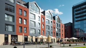 a group of tall buildings with tables and umbrellas at Apartamenty Chmielna 72 in Gdańsk