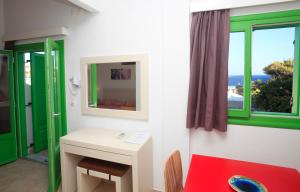 Habitación con mesa, espejo y ventana. en Kastellos Apartments Sikinos en Alopronia