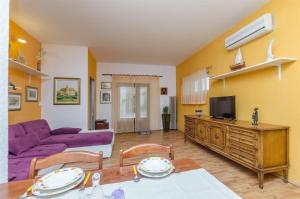 a living room with a purple couch and a tv at Apartments Amulic in Duće