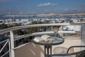 einen Balkon mit einem Tisch mit einem Buch und einem Glas Wein in der Unterkunft Nice Sea View Elegant Apartment in Athen