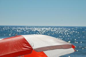 a red and white umbrella in front of the ocean at Hotel Eur in Lido di Camaiore