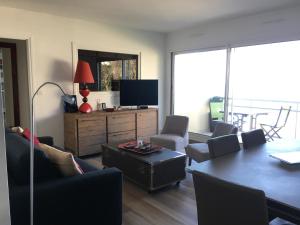 sala de estar con TV, mesa y sillas en Appartement, vue mer à 150m de la plage, en Trouville-sur-Mer