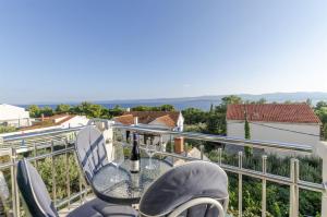 a table and chairs on a balcony with a bottle of wine at Apartments and Room Villa Niko in Bol