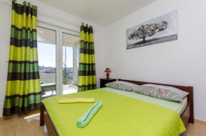 a bedroom with a green bed with a window at Apartments Matan in Sevid