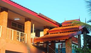 une maison avec un toit rouge et un palmier dans l'établissement Boutique House Nipha, à Chiang Mai