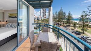 a balcony with a bed and chairs and a view of a street at Oaks Gold Coast Calypso Plaza Suites in Gold Coast