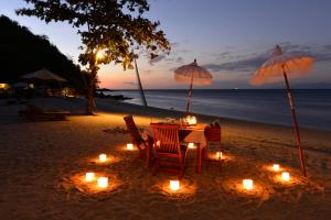 a table with candles and umbrellas on the beach at Cocotinos Sekotong Lombok in Sekotong