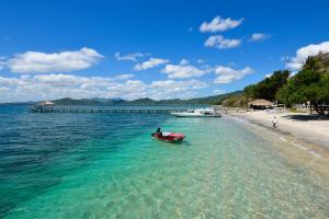 a red boat in the water next to a beach at Cocotinos Sekotong Lombok in Sekotong