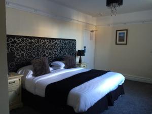 ein Schlafzimmer mit einem großen Bett mit einer schwarzen und weißen Decke in der Unterkunft The Eagles Hotel in Llanrwst