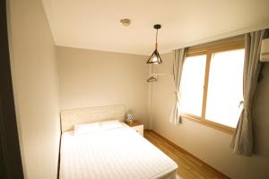 
a bedroom with a bed and a window at Yeha Guesthouse in Jeju
