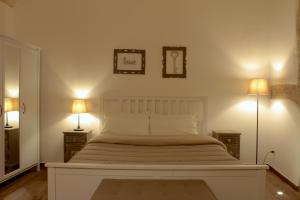 een slaapkamer met een groot wit bed met 2 lampen bij DeShome Guest House in Bari