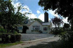 a white house with a chimney on a driveway at Rosedene Guest House in Pembroke