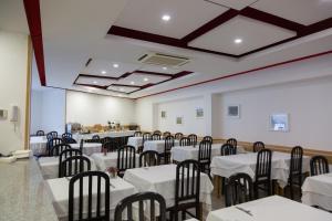 um salão de banquetes com mesas e cadeiras brancas em Troia Hotel em Amares