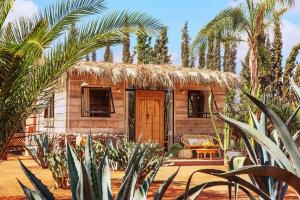 a small house with a thatched roof and palm trees at The Source Hotel Music & Spa in Marrakech