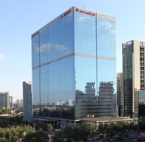 a tall glass building in a city with tall buildings at Grand Concordia Hotel in Beijing