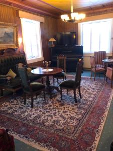 a living room with a table and chairs and a piano at Bygdin Høyfjellshotell in Beitostøl