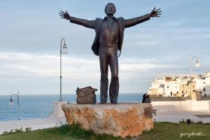 a statue of a man with his arms out at case per vacanze torre incina in Polignano a Mare