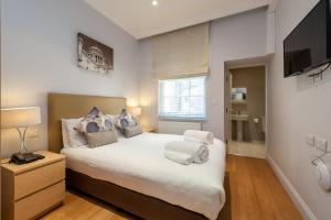a bedroom with a large bed and a television at 12 London Street Apartments in London