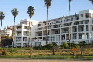 a white building with palm trees in front of it at Point Village Accommodation - Santos 61/62 in Mossel Bay