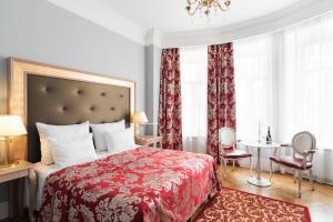1 dormitorio con cama roja, mesa y sillas en Demetra Art Hotel en San Petersburgo