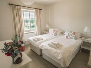 a white bedroom with two beds and a window at Holly Farm in Doddington