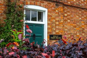 una puerta verde con una señal frente a un edificio de ladrillo en Holly Farm, en Doddington