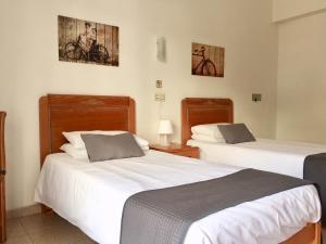 a hotel room with two beds and two lamps at Casa d’Hostes Cala Millor in Cala Millor