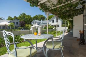 eine Terrasse mit einem Tisch und Stühlen unter einer Pergola in der Unterkunft Le Quartier Francais in Franschhoek