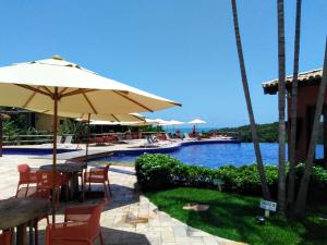 ein Pool mit Tisch, Stühlen und Sonnenschirm in der Unterkunft Chalé coco b4 in Maceió