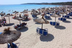 カラ・ミラーにあるSol y Luna Cala Millorの多くの椅子とパラソルと海を備えたビーチ