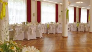 einen Bankettsaal mit weißen Tischen und weißen Stühlen in der Unterkunft Hotel Goldener Fasan in Oranienbaum-Wörlitz
