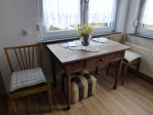 een houten tafel met twee stoelen en een vaas met bloemen erop bij Ferienwohnung bei Michels in Ober-Kinzig