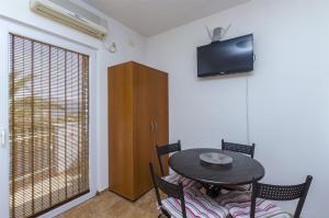 a dining room with a table and a television on the wall at Apartments Jozsef in Splitska